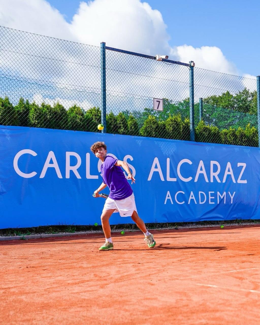 Młody tenisista przy siatce na tle baneru Carlos Alcaraz Academy — Kozerki 2026